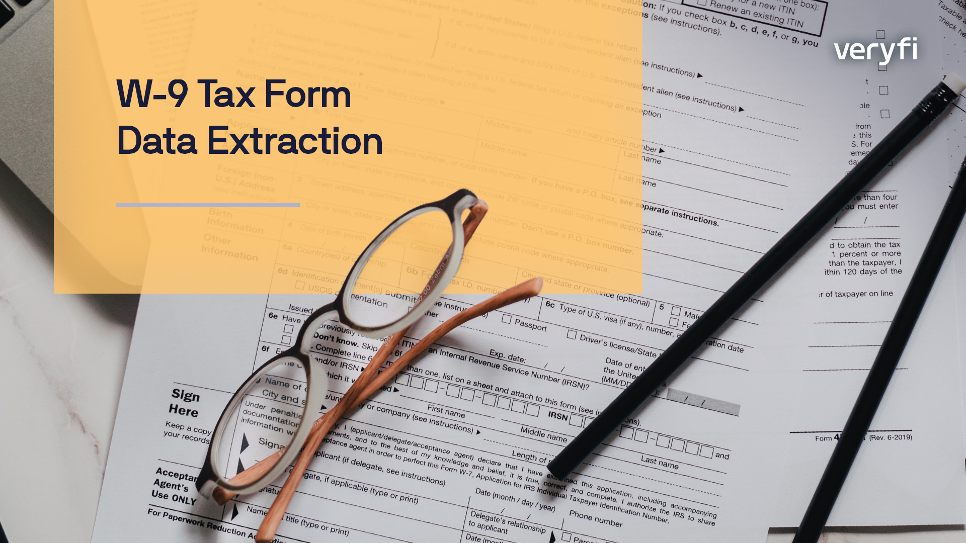 Some tax form documents on a desk with a pair of reading glasses and pen.